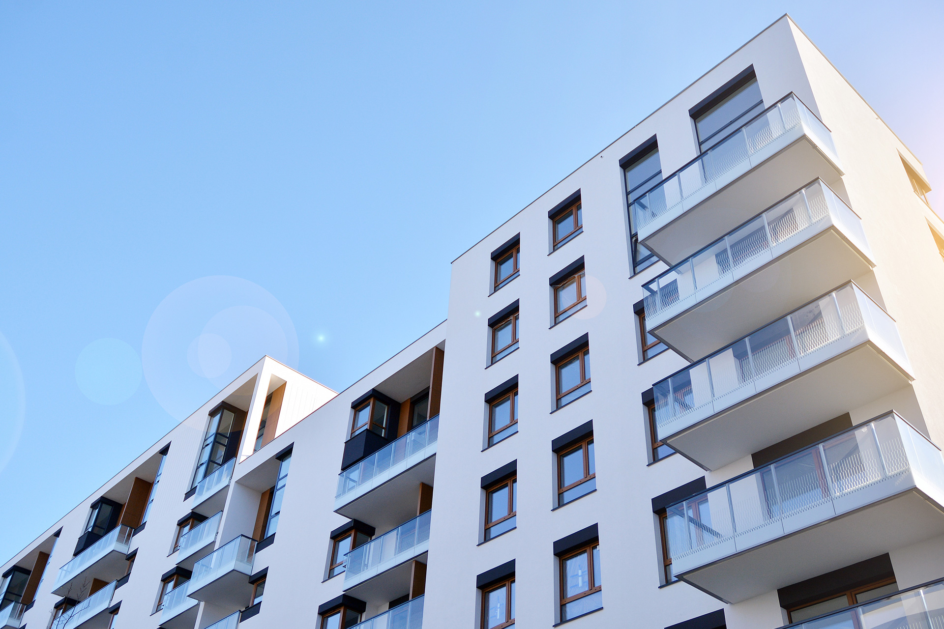Moderne Mehrfamilienhäuser mit Balkonen unter blauem Himmel – Hausverwaltung inveni consulting