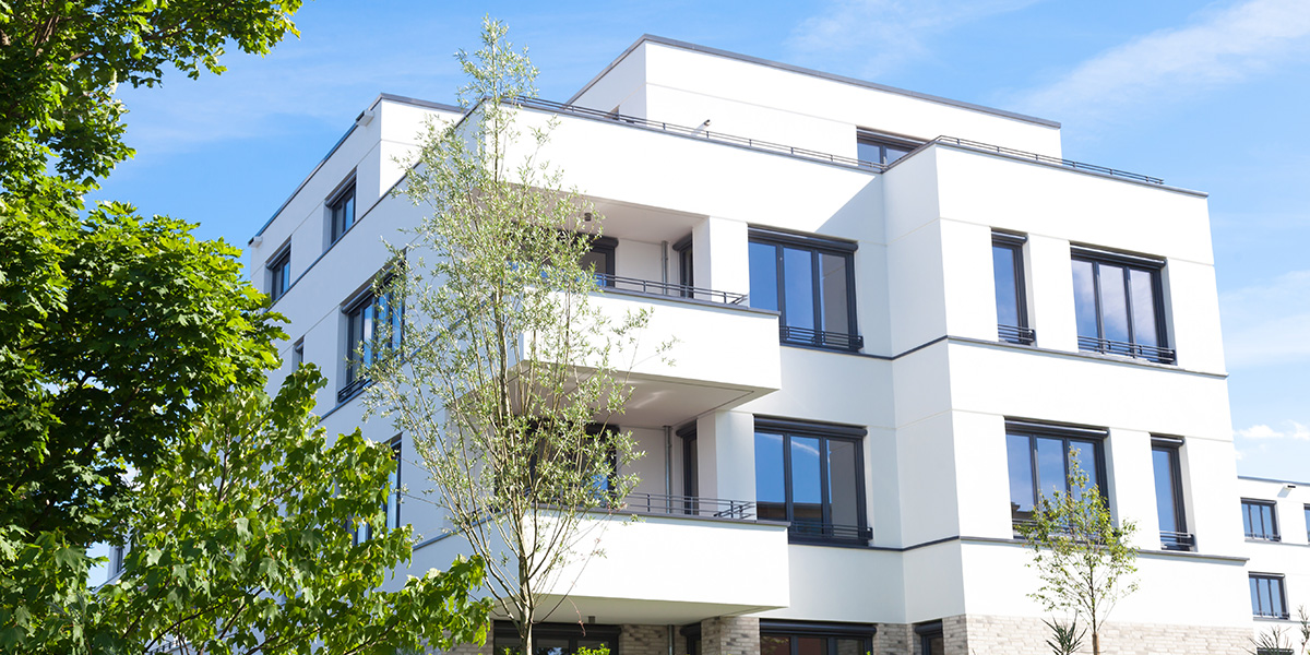 Modernes Mehrfamilienhaus mit Balkonen, umgeben von grünen Bäumen, verwaltet von inveni consulting als Teil unseres Mietverwaltungsportfolios.