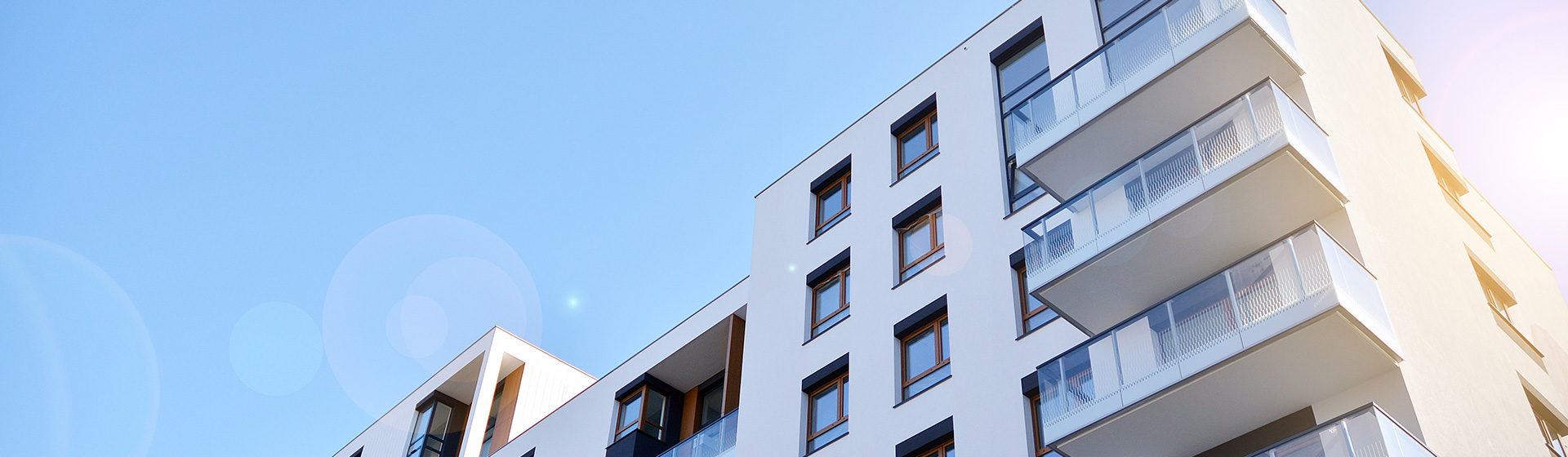 Moderne Mehrfamilienhäuser mit Balkonen unter blauem Himmel – Gewerbeverwaltung inveni consulting 